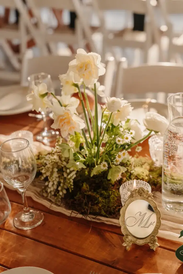 Timber reception table centrepiece of white flowers and moss