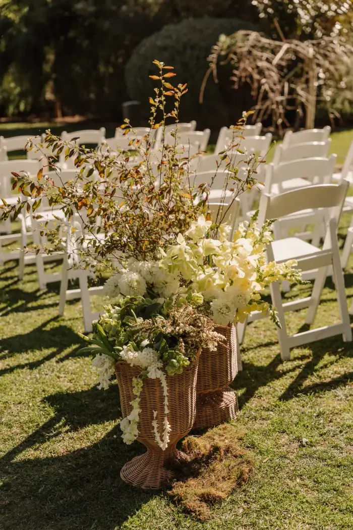 Aisle arrangement of white and yellow flowers in a woven basket