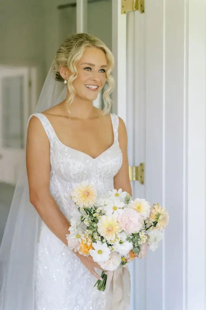Bride in a doorway holding a peach and cream bridal bouquet